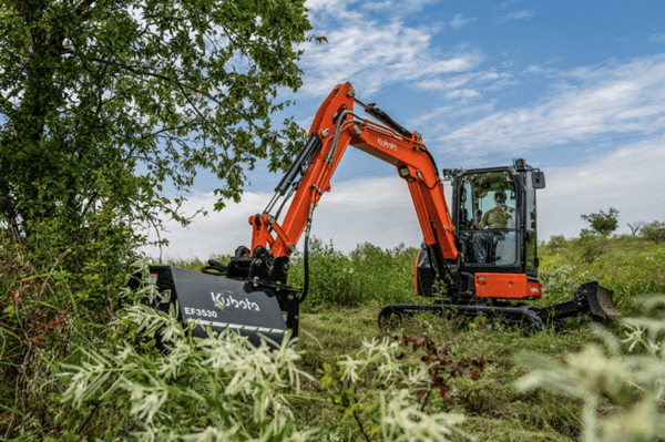 Excavator using mowing attachment to clear of thick brush